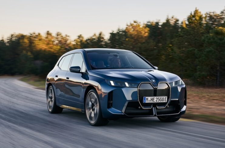 BMW IX auf der Strasse beim Fahren vor einem Wald