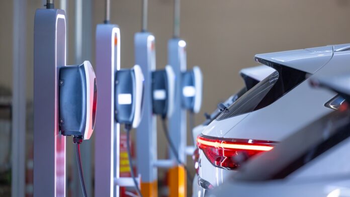 BALANCE Ladeinfrastruktur EV-Ladegerät und Elektroauto, Ladestation für Elektroautos zum Laden der EV-Batterie, Stecker für Fahrzeuge mit Elektromotor, EV-Ladegerät für saubere Energie, Ladestation auf dem Parkplatz eines Kaufhauses.